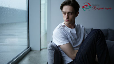 Молодой человек сидит у окна